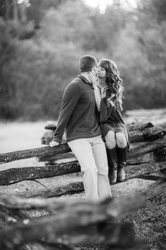 black and white photo of couple kissing on wooden fence