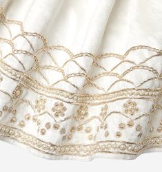 a white dress with gold threadwork on it