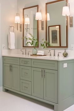 a bathroom with two sinks, mirrors and lights on the wall above them is shown