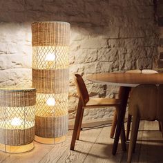 two lamps sitting next to each other on top of a wooden table in front of a stone wall