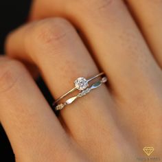 a woman's hand with a diamond ring on top of her finger and an engagement band