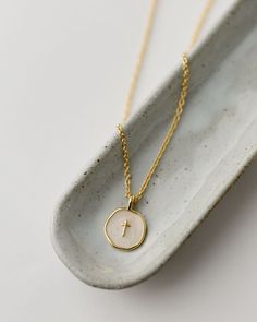 Sure to be a new customer favorite, our Emily Necklace is a modern addition to our spiritual jewelry line. We love with the dainty ivory and gold enamel disc with tiny gold cross for Easter and Confirmation gifting, but don't forget to grab one for yourself, too! Details: Gold plated brass 16" chain with 2" extender Handmade in Haiti Gold-plated and ivory enamel cross pendant Cheap Minimalist Cross Pendant Necklace, Cheap Adjustable Cross Pendant Necklace, White Cross Necklace With Medium-length Chain, White Cross Necklace With Adjustable Chain, Spiritual Cream Jewelry Gift, Spiritual Cream Jewelry For Gift, Spiritual Cream Jewelry As Gift, Spiritual Cream-colored Jewelry For Gift, Delicate Beige Jewelry Gift