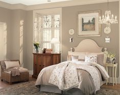 a bed room with a neatly made bed and a chandelier above the bed