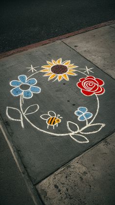 a painted flower and bee design on the sidewalk in front of a bus stop sign