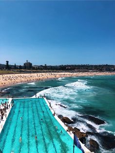 an outdoor swimming pool next to the ocean with people on it and in the water