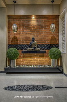 a statue sitting on top of a bench next to two potted plants in front of a brick wall