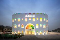 a large white building with arched windows and colorful lights on it's front entrance