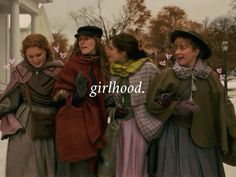 three women standing next to each other in front of a building with the words girlhood written on it