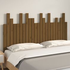 the headboard is made from wood and has white linens on top of it