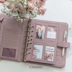 an open pink planner book with photos on it and flowers in the vase next to it