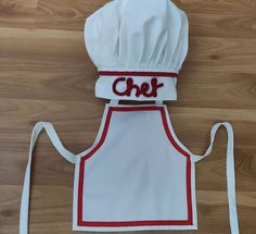 a chef's apron with the word chef written on it, sitting on top of a wooden floor