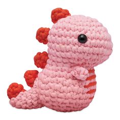 a crocheted pink and orange dragon stuffed animal sitting on its back with two legs