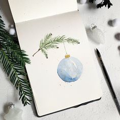 a christmas ornament is hanging from a tree branch on top of a notebook