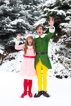 a man and woman dressed in elf costumes standing next to each other on snow covered ground