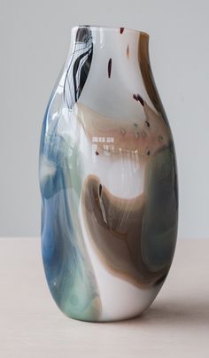 a white and blue vase sitting on top of a wooden table next to a wall