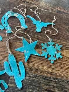 some ornaments are hanging on a wooden table with string and snowflakes attached to them