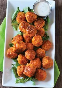 a white plate topped with meatballs and lettuce next to a dipping sauce