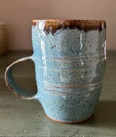 a blue coffee cup sitting on top of a wooden table