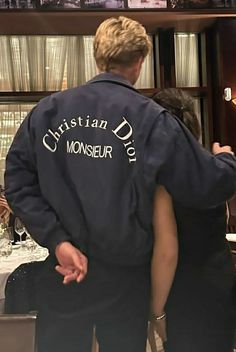 a man and woman standing next to each other in front of a table with wine glasses on it