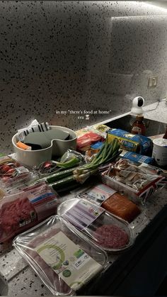 an assortment of meats and vegetables sitting on a counter top next to a sink