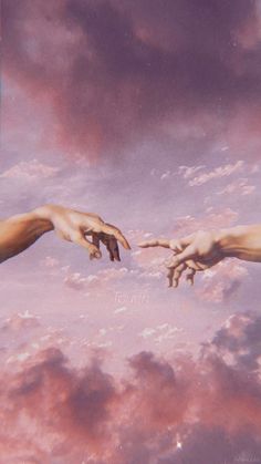 two hands reaching out towards each other in the sky with clouds and pink hues