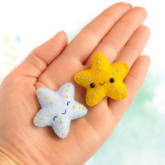 two little stars are sitting on someone's hand, one is yellow and the other is white