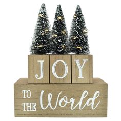 a wooden block with christmas trees on it and the words joy to the world written in white