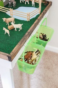 toy farm animals in plastic bins on top of a table with grass and dirt