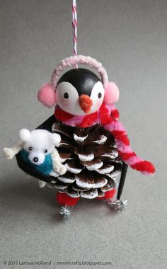 an ornament with a penguin holding a pine cone and two small white bears