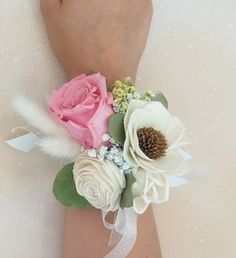 a woman's arm with flowers and feathers attached to it, on top of a white surface