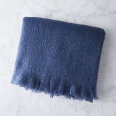 a blue blanket laying on top of a white marble counter next to a black object