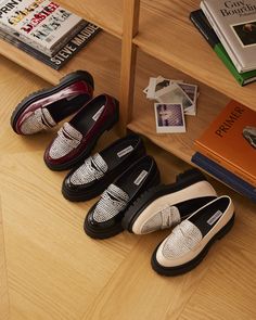 five pairs of shoes are lined up on the floor next to books and an open bookcase