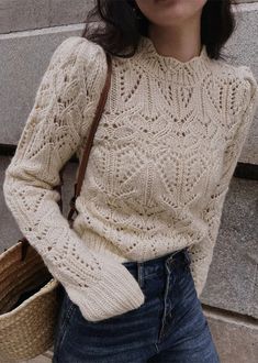 a woman is holding a basket and wearing a sweater