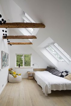 an attic bedroom with white walls and wooden floors, along with exposed beams on the ceiling