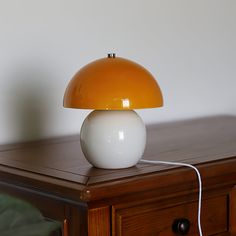 an orange and white lamp sitting on top of a wooden table