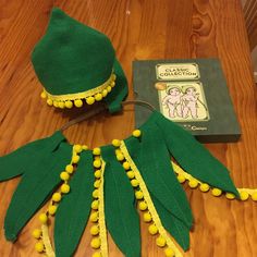 a green hat with yellow pom - poms and a book on the table