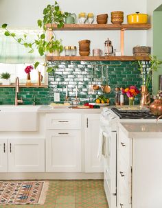 a kitchen filled with lots of white cabinets and counter top space next to a green tiled backsplash