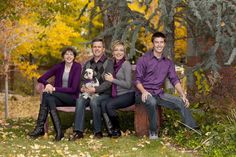 a family sitting on a bench in the fall