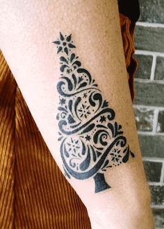 a woman's arm with a tattoo on it that has a christmas tree in the center