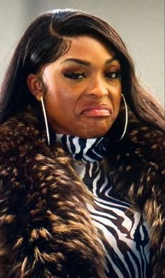 a woman in a zebra print coat and hoop earrings looking at the camera with an angry look on her face