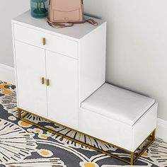 a white cabinet with a pink purse on top and a blue vase next to it