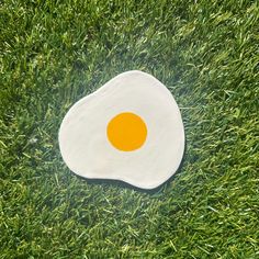 an egg is laying in the grass on top of it's side, which has been painted orange and white