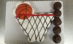 a cake made to look like a basketball net with chocolates on the rim and an orange ball hanging from it