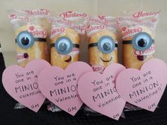 three minion valentines with blue eyes and pink heart shaped tags in front of them