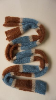 three knitted scarves sitting on top of a white table next to each other