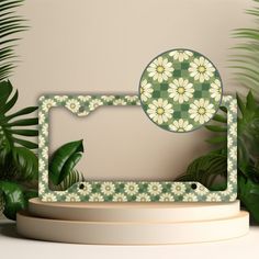 a photo frame sitting on top of a table next to some green leaves and plants