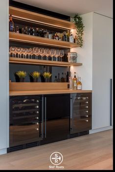 an empty bar with wine glasses and bottles on the shelves in this modern home office