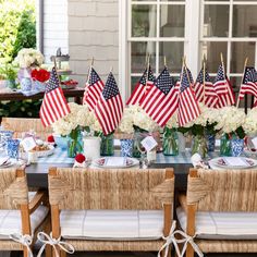 an outdoor table set with american flags and flowers