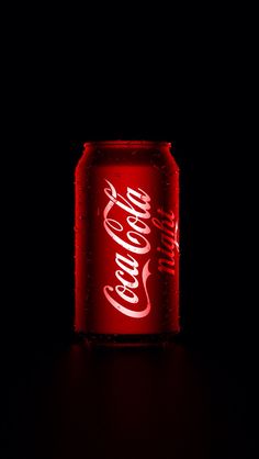 a can of coca - cola lit up in the dark