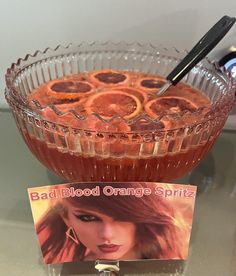 a glass bowl filled with blood orange spiritz on top of a table next to a magazine